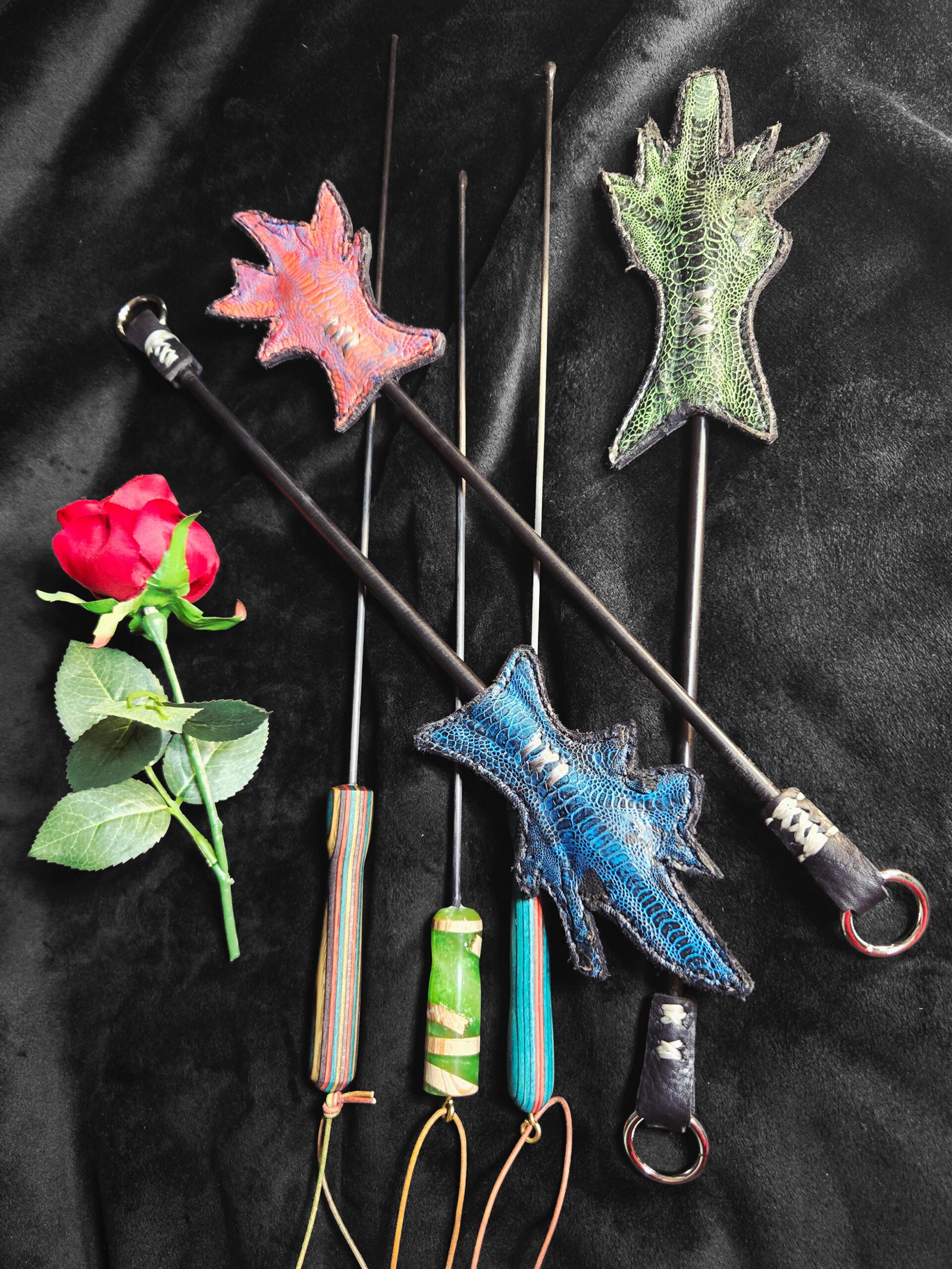 Handcrafted Evil Sticks and Chicken-on-a-Stick crops featuring exotic leather designs, colorful handles, and decorative accents, displayed alongside a rose on a black background.