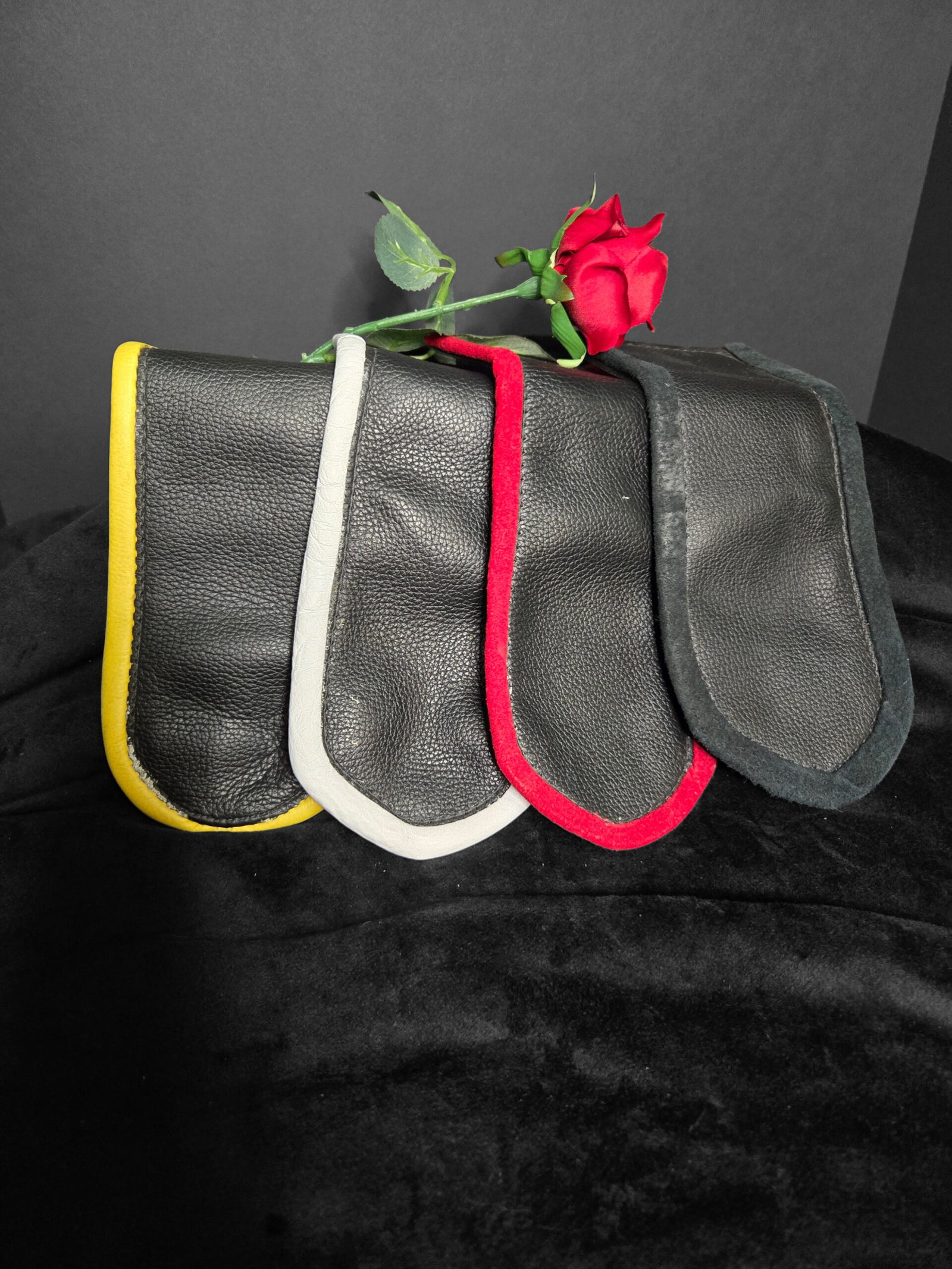 Leather pocket flags in black with colorful accents (yellow, white, red, and grey) and a red rose, showcasing unique handcrafted design for lifestyle signaling by W.E.L.P.
