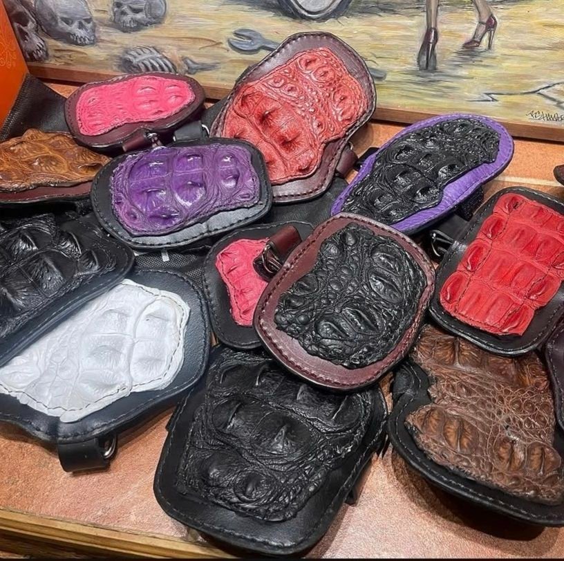 Assorted handcrafted leather paddles in various colors, showcasing intricate textures and designs, emphasizing artisan quality and durability for BDSM use.