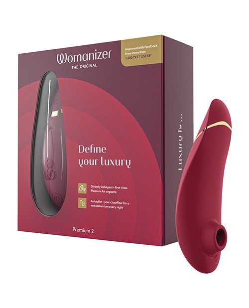 Womanizer Premium 2 clitoral suction toy in red and black packaging, featuring "Define your luxury" tagline, showcasing advanced Pleasure Air technology for contactless stimulation, highlighted as a best seller on Crave Romance Boutique.
